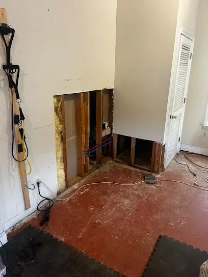 Drywall cut away at the base of a wall to dry the cavity after a burst pipe